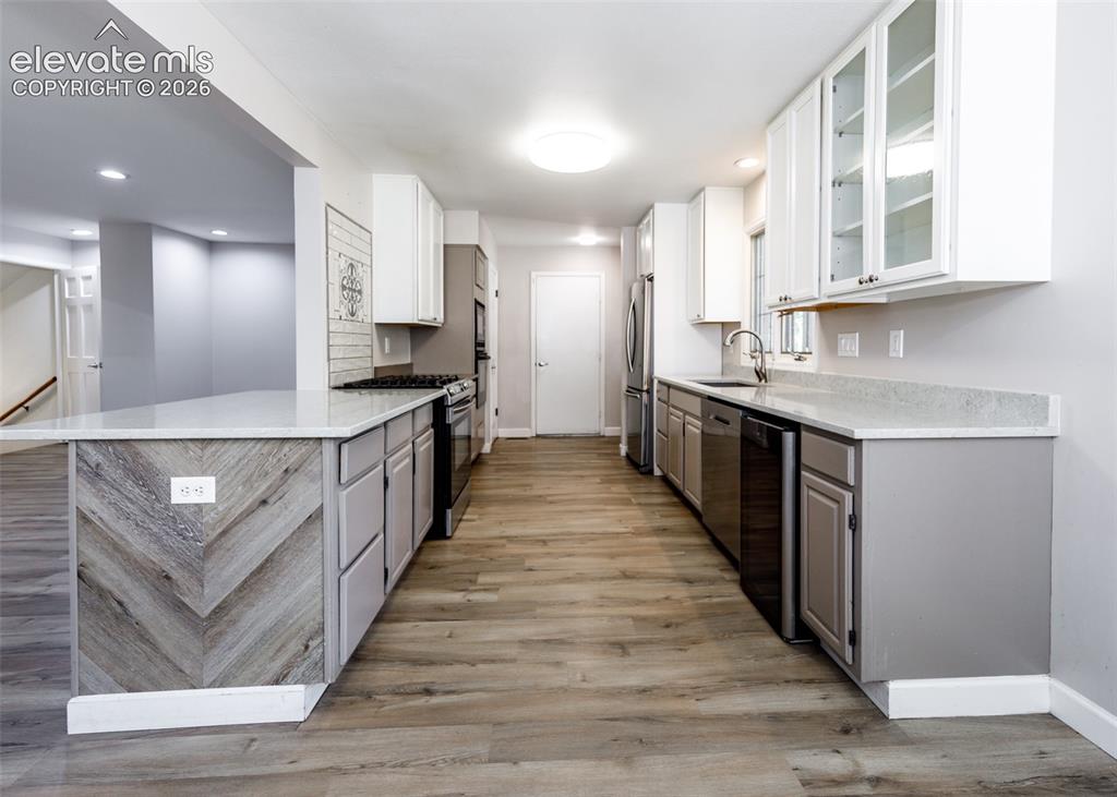 Image 20 of 44: Kitchen featuring wood-finish flooring, two-tone cabinetry, stainless steel