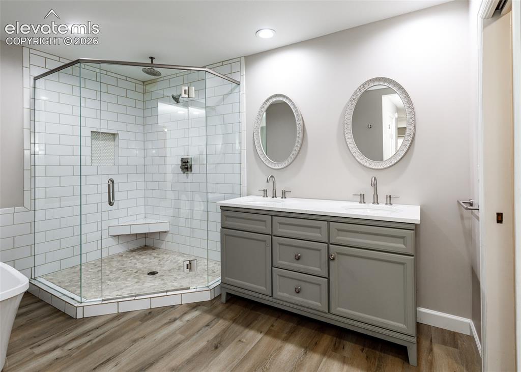 Image 26 of 44: Glass-enclosed shower with white subway tile, built-in bench, and tiled flo