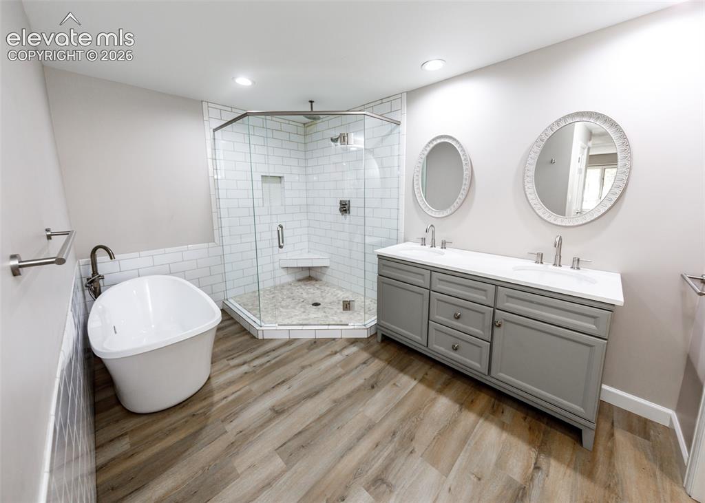Image 27 of 44: Freestanding soaking tub, wood-finish flooring, glass-enclosed shower with 