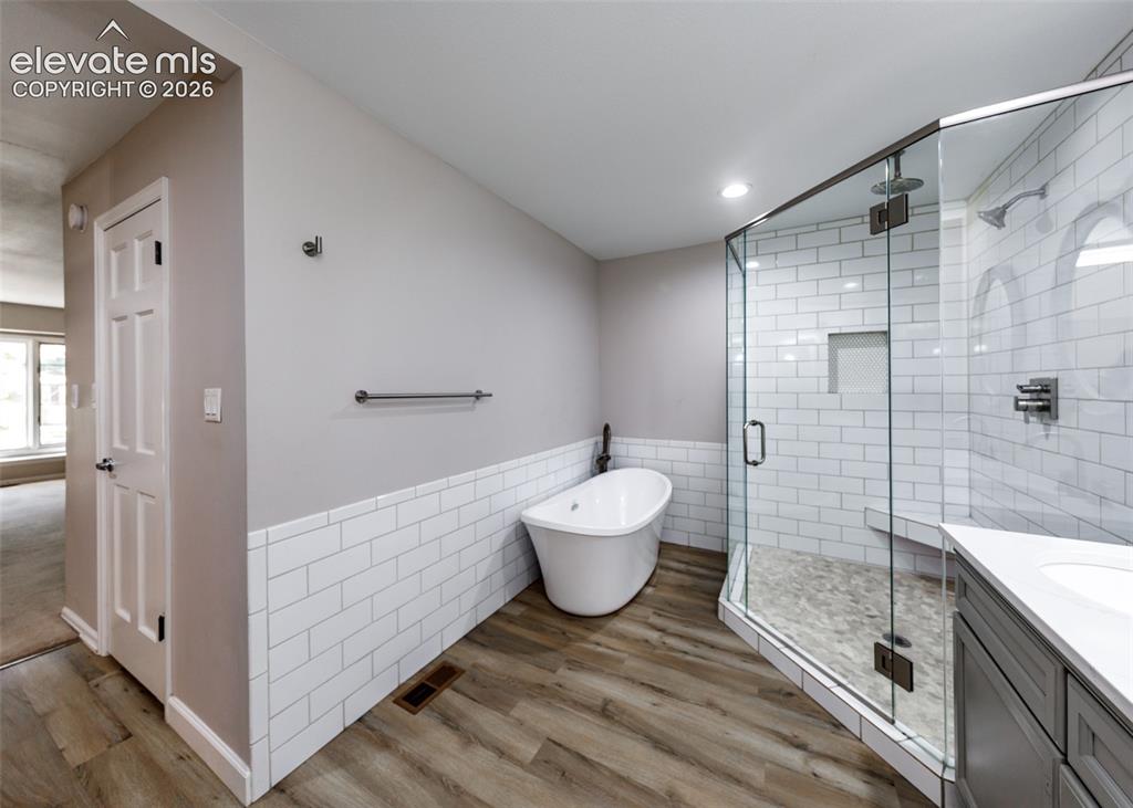Image 28 of 44: Freestanding soaking tub, walk-in shower with clear glass enclosure and til