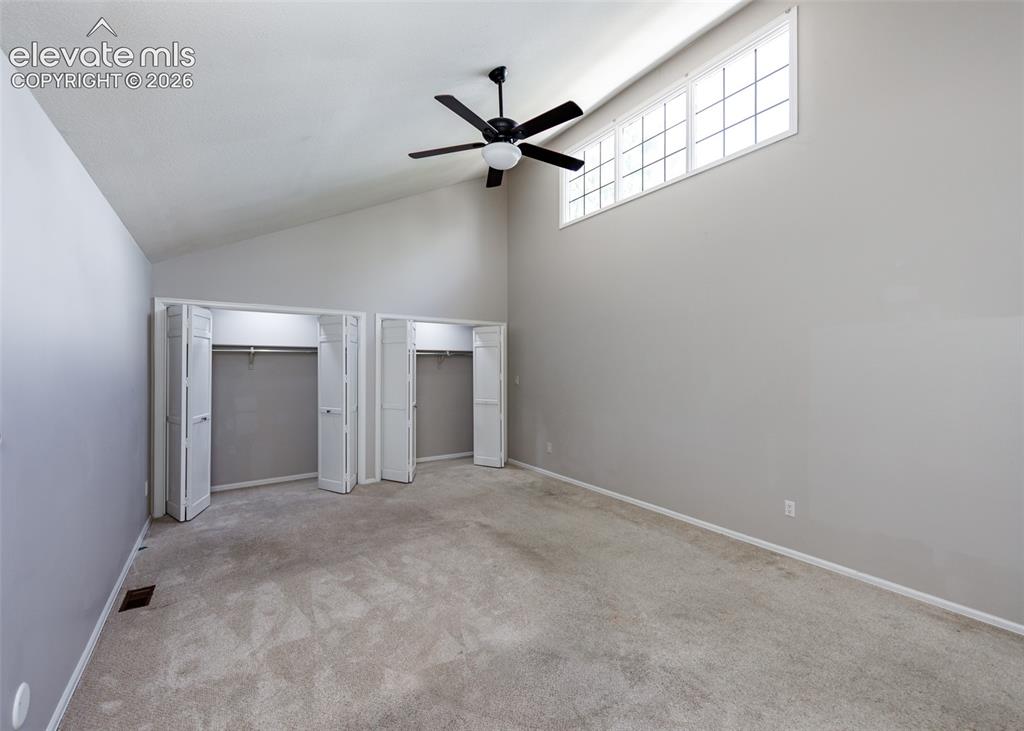 Image 35 of 44: Vaulted ceiling with an integrated ceiling fan, transom windows, and built-