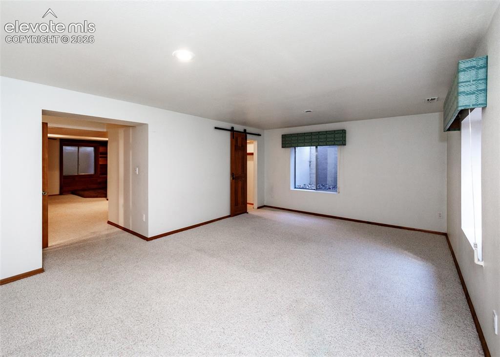 Image 37 of 44: Carpeted flooring, recessed lighting, and a barn door entry