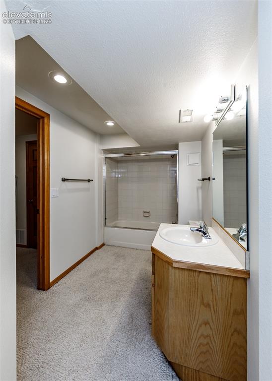 Image 43 of 44: Bathroom featuring a white bathtub with tile surround, wood-finish vanity, 