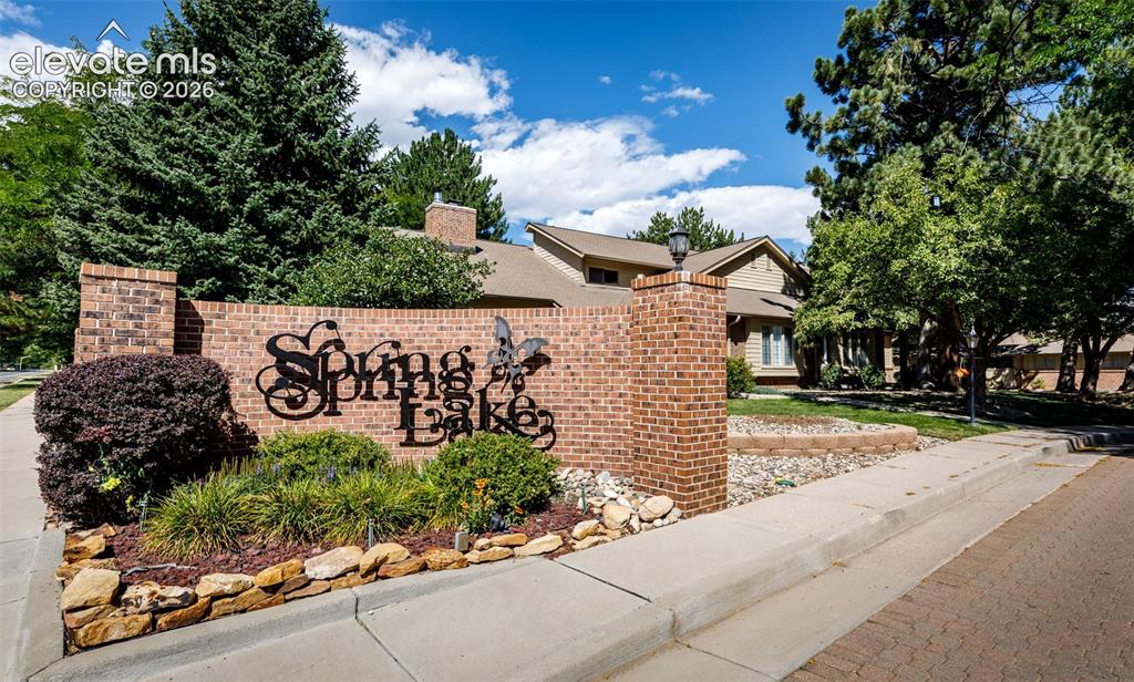 Image 44 of 44: Brick entry monument with wrought iron lettering, complemented by mature la