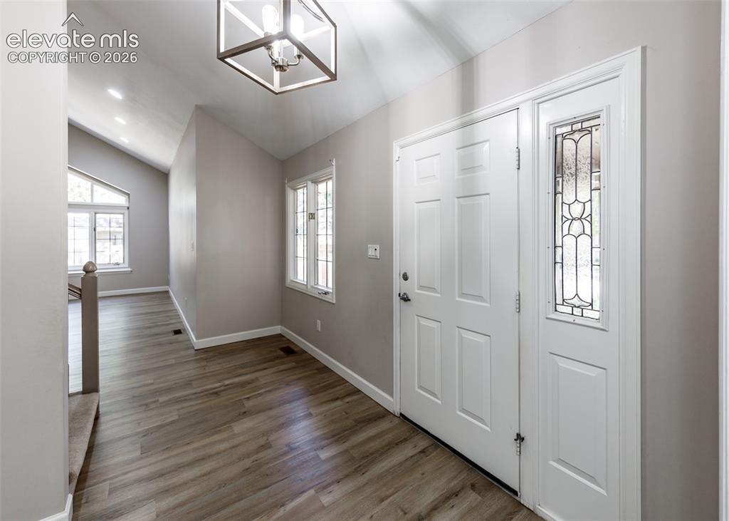 Image 7 of 44: Entryway featuring wood-finish flooring, vaulted ceilings, and a decorative