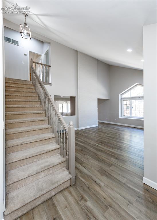 Image 9 of 44: Two-story foyer with a carpeted staircase and wood-finish flooring