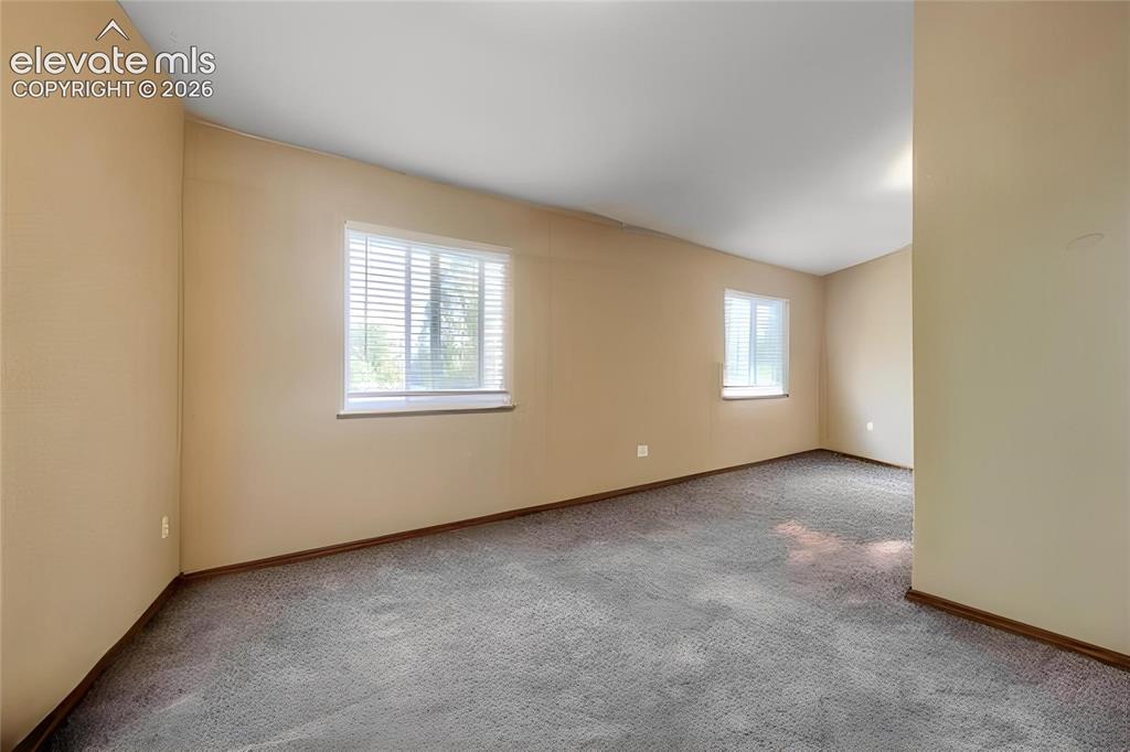 Image 10 of 19: Neutral-toned walls, two windows with blinds, and gray carpeting