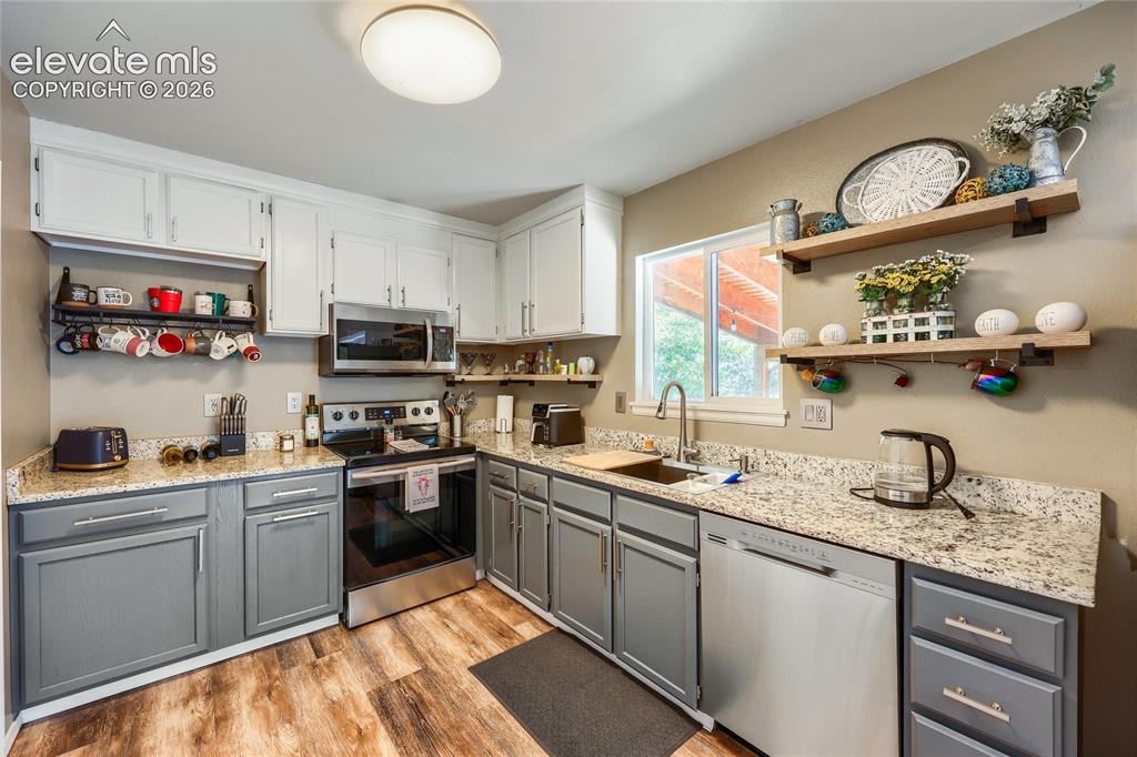 Image 12 of 19: Kitchen featuring two-tone cabinetry, wood-finish flooring, stainless steel