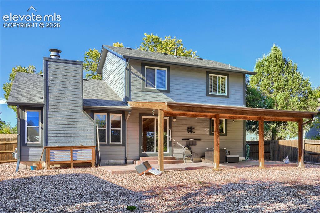 Image 18 of 19: Exterior featuring gray siding, a covered patio with wood posts, a paved pa