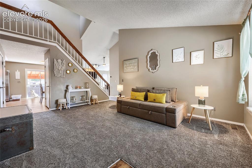 Image 5 of 19: High ceilings, staircase with wood handrail, textured gray carpeting, neutr