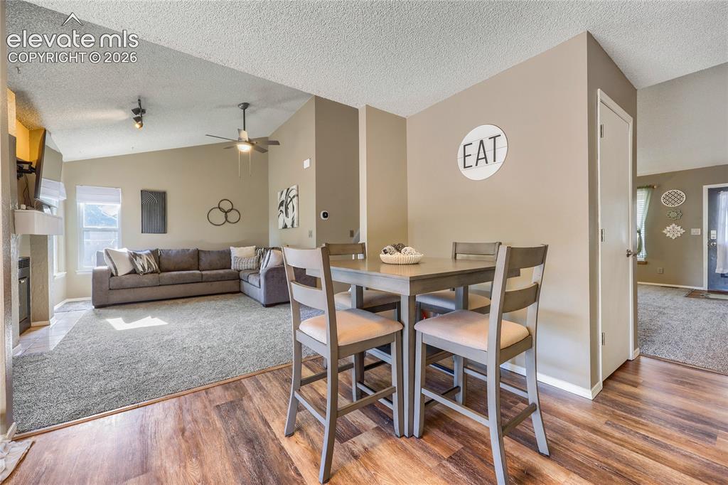 Image 8 of 19: Vaulted ceiling with ceiling fan, fireplace with mantel, wood-finish floori