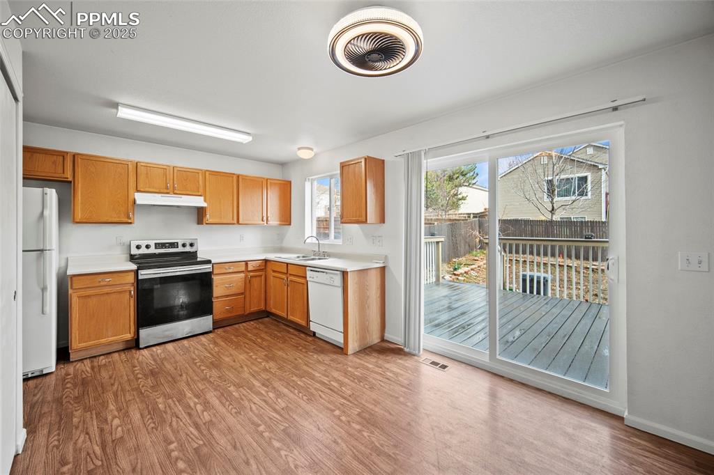 Image 15 of 43: Kitchen with light countertops, a sink, wood finished floors, under cabinet