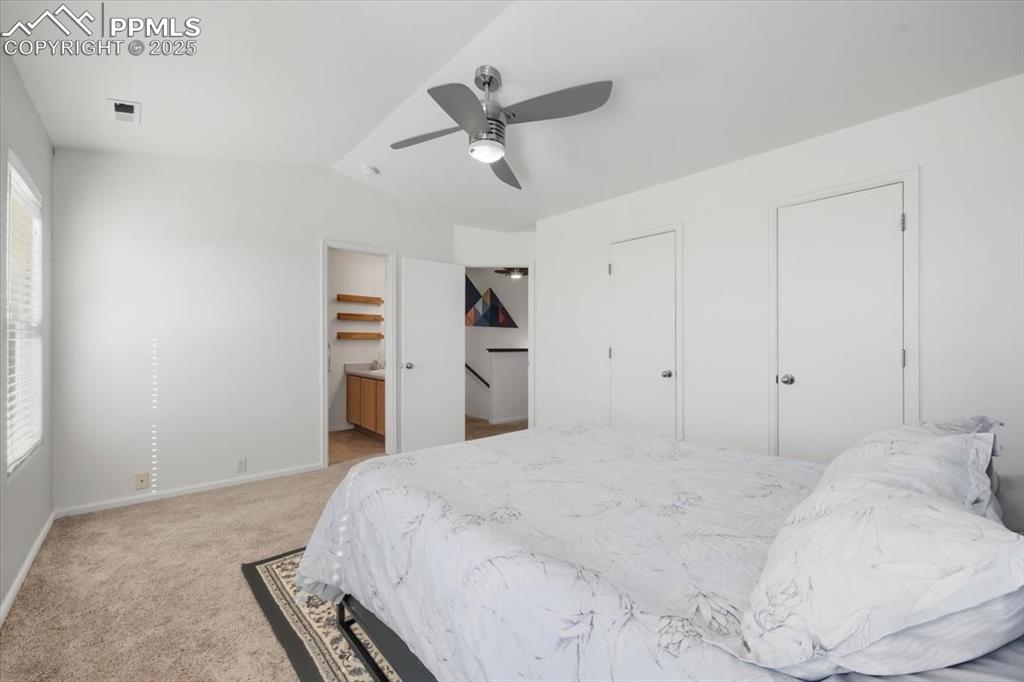 Image 18 of 36: Bedroom with light carpet, ceiling fan, vaulted ceiling, and multiple close