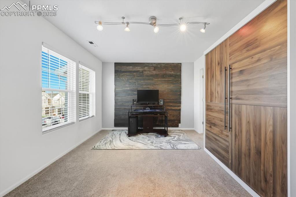 Image 22 of 36: Bedroom with an accent wall and carpet
