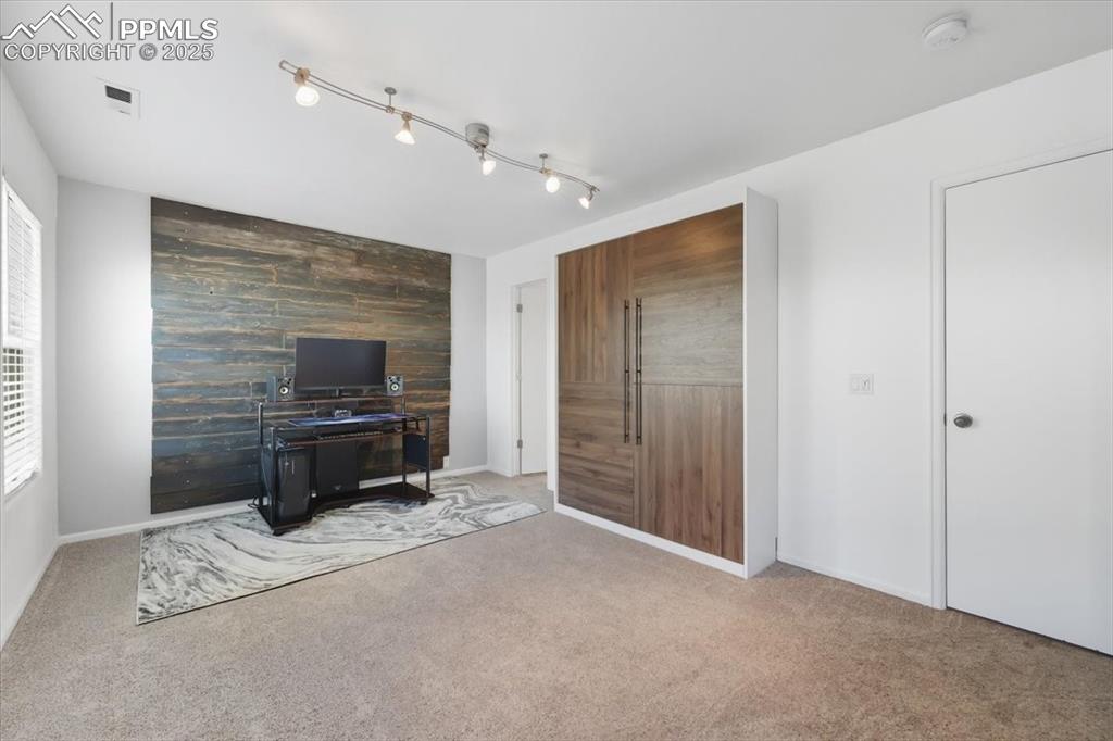Image 23 of 36: Bedroom with an accent wall and carpet