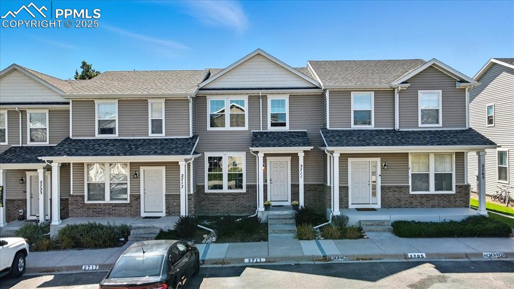 Image 35 of 36: View of front facade featuring brick siding, uncovered parking, and a shing