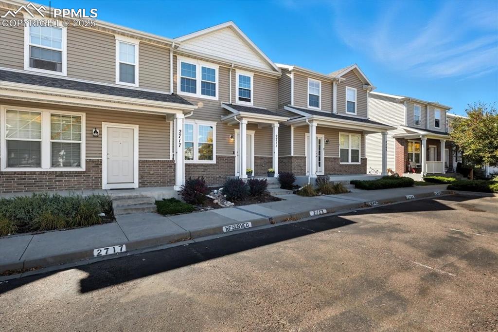 Image 36 of 36: View of front of home with brick siding, covered porch, and a residential v