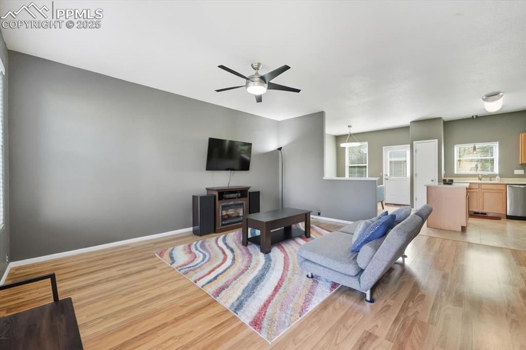 Image 4 of 36: Living room with light wood finished floors and a ceiling fan