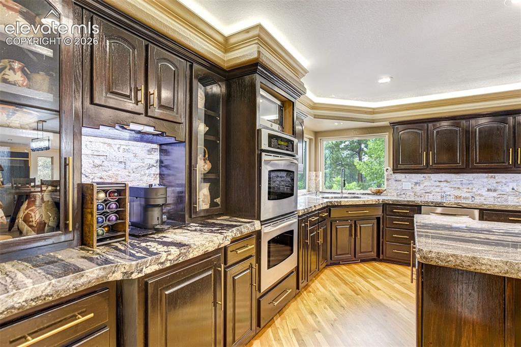 Image 13 of 40: Dark wood cabinetry, stone countertops, stainless steel double oven, stainl