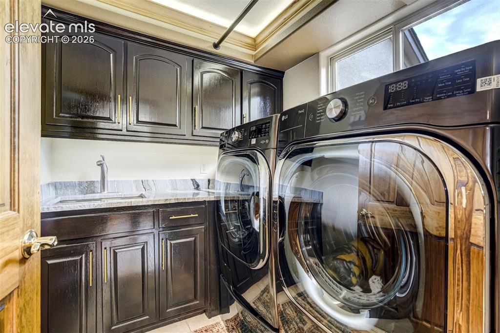 Image 18 of 40: Laundry area featuring dark wood cabinetry, a built-in sink with a goosenec