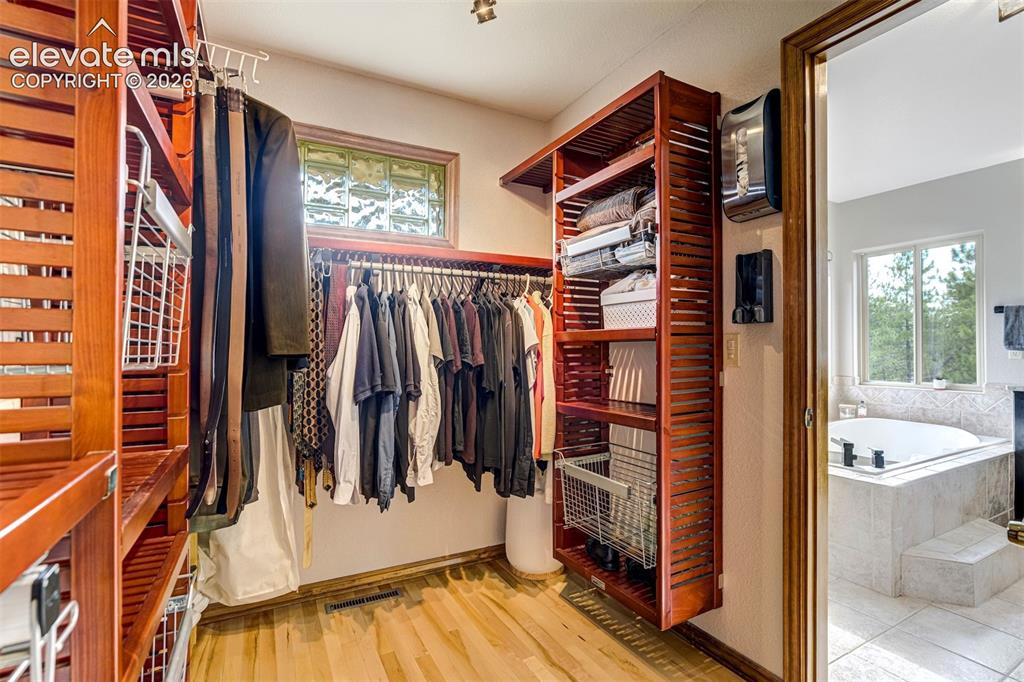 Image 21 of 40: Custom closet organization system with wood-finish shelving and hanging rod