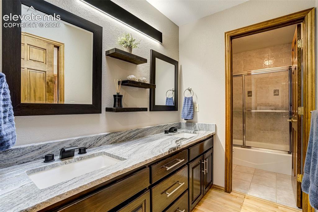 Image 27 of 40: Dual vanity with integrated sinks, patterned stone countertop, dark wood-fi
