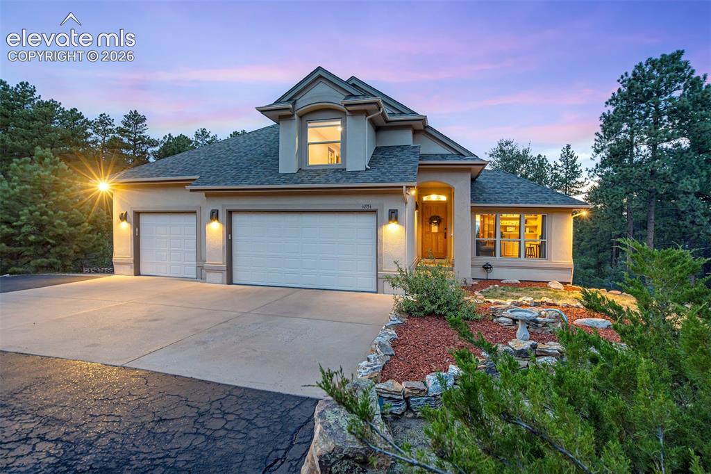Image 3 of 40: Stucco exterior with a three-car garage with EV charger. concrete driveway,