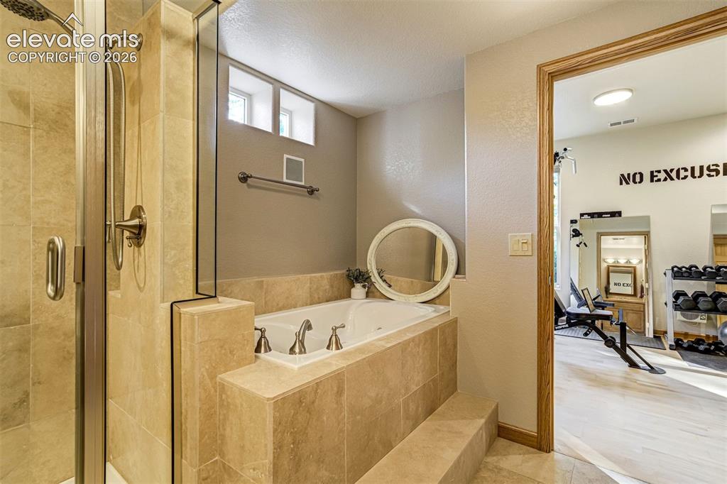 Image 33 of 40: Tiled soaking tub with stepped surround, glass-enclosed shower, and translu