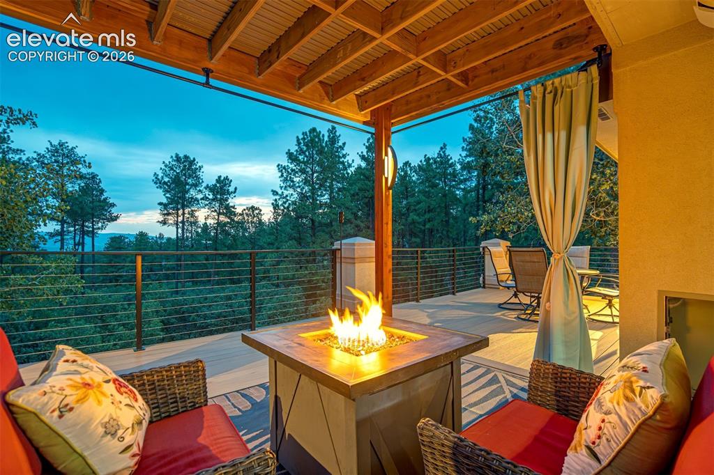 Image 35 of 40: Covered outdoor deck featuring a wooden beam ceiling, a built-in fire pit, 