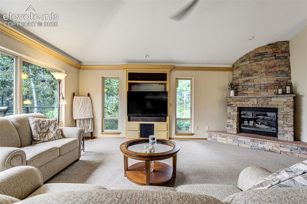 Image 9 of 40: Stone-clad fireplace with a hearth, built-in entertainment center, and larg