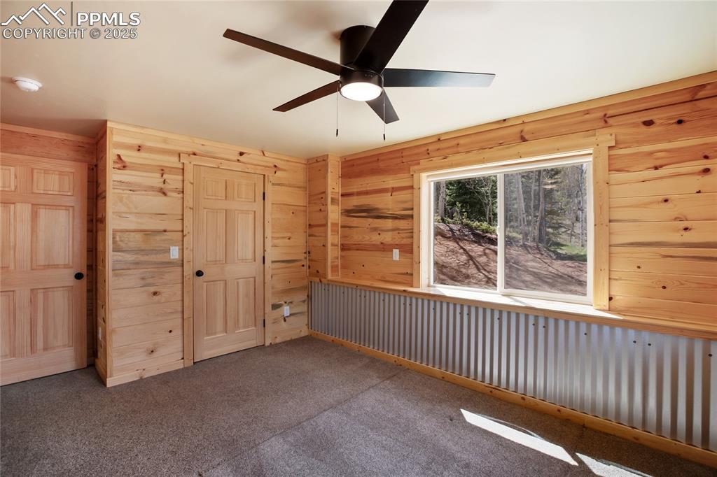 Image 17 of 45: Unfurnished bedroom featuring wooden walls, carpet, a closet, and a ceiling