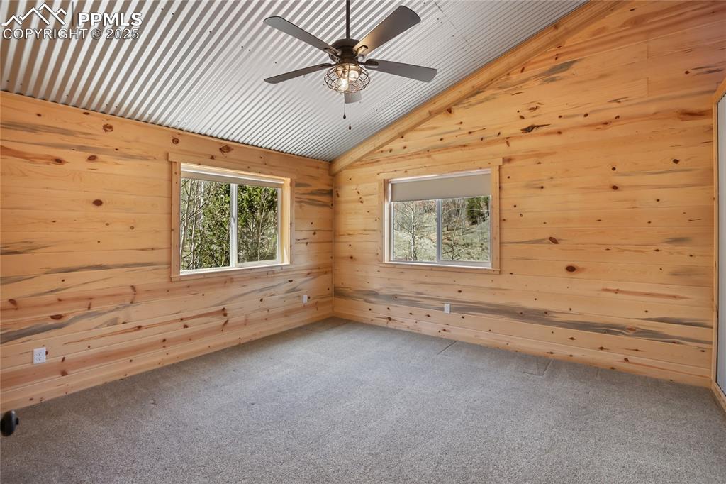 Image 24 of 45: Bedroom #3 with pine paneling, carpet and ceiling fan. Lots of natural ligh