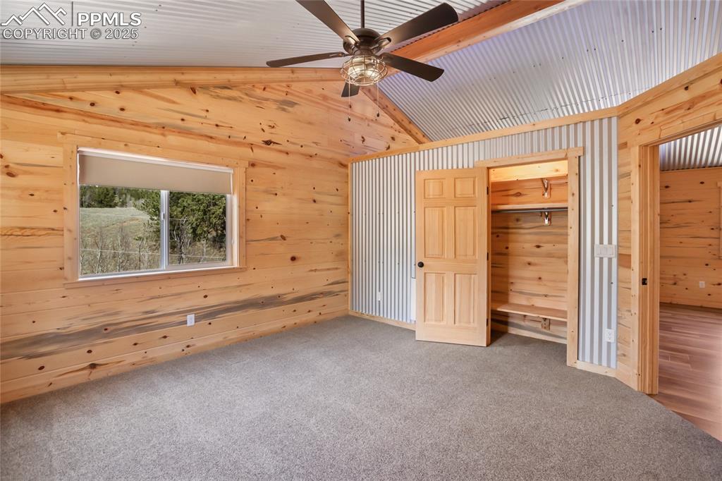 Image 26 of 45: Bedroom #3 with pine paneling, metal accents, carpet floors and ceiling fan