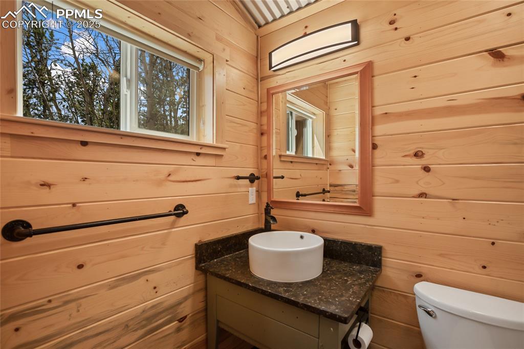 Image 27 of 45: Upstairs bathroom with pine paneling, vanity, and toilet