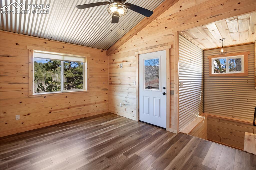 Image 33 of 45: Unfurnished room with wooden walls, plenty of natural light, vaulted ceilin