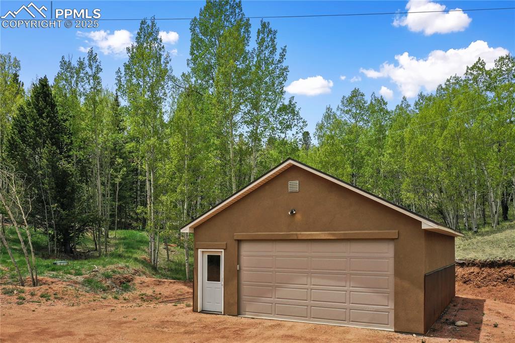 Image 4 of 45: Detached garage featuring a forest view