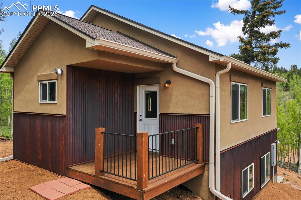 Image 44 of 45: Rear view of property featuring a deck, stucco siding, and roof with shingl