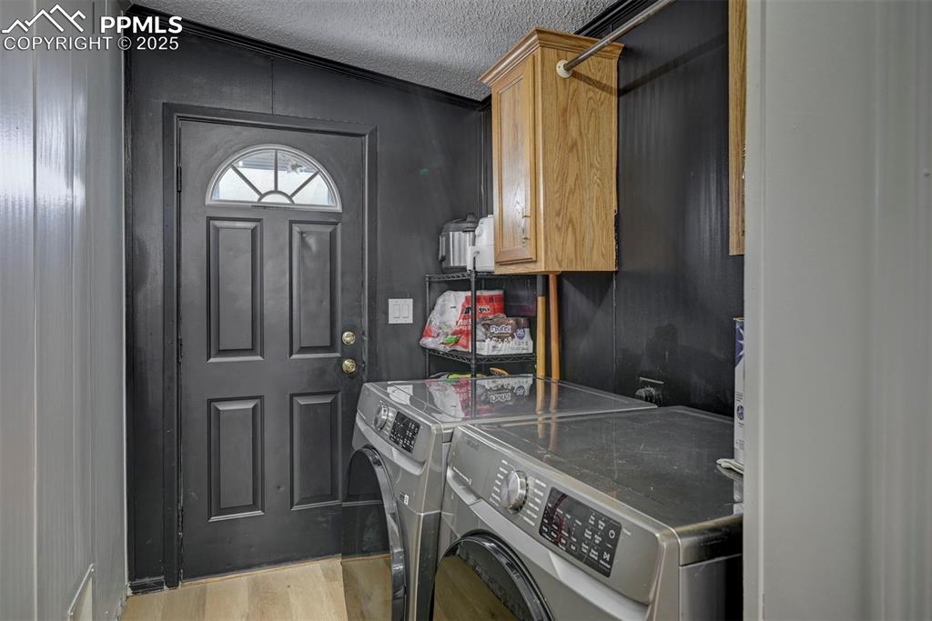 Image 14 of 40: Laundry area with light wood-type flooring, a textured ceiling, washer and
