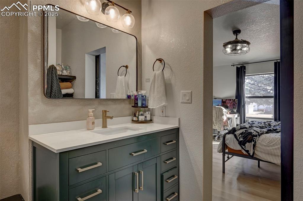 Image 18 of 40: Bathroom with a textured wall, ensuite bath, vanity, light wood-style floor