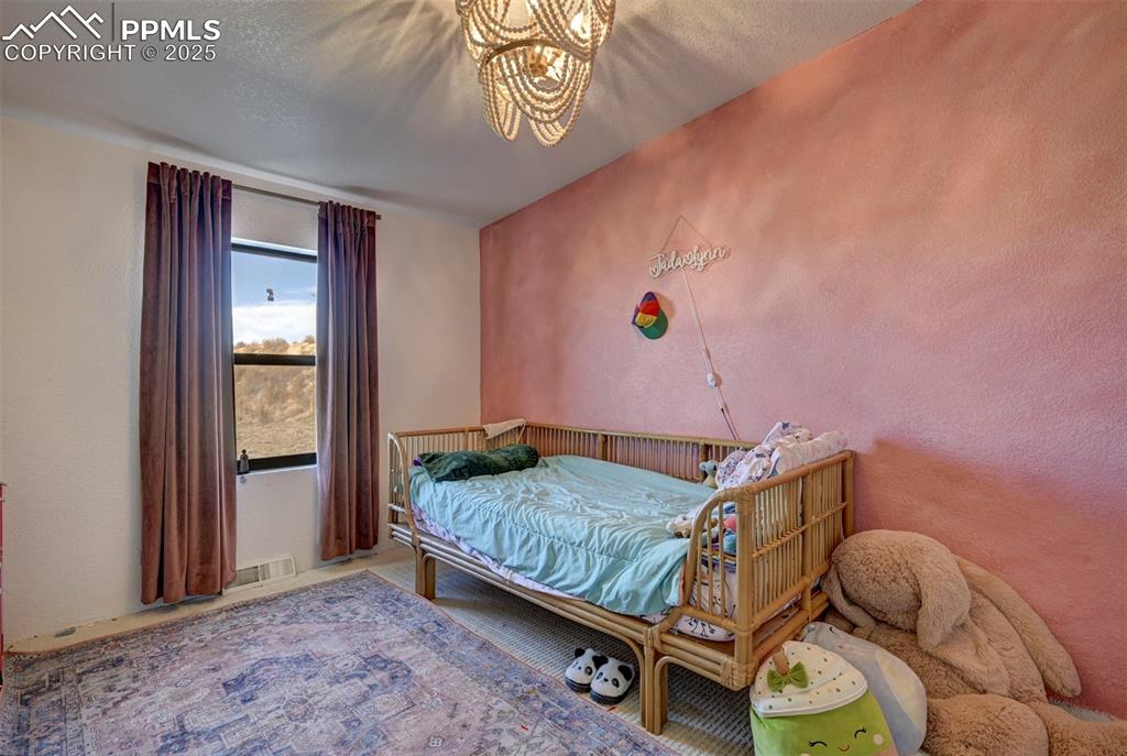 Image 22 of 40: Bedroom featuring a textured wall, a chandelier, and a textured ceiling