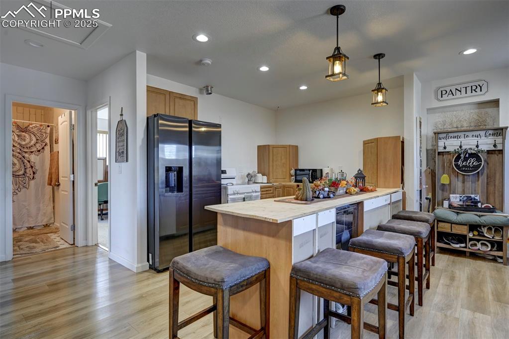 Image 28 of 40: Kitchen with light countertops, stainless steel fridge, a breakfast bar, li