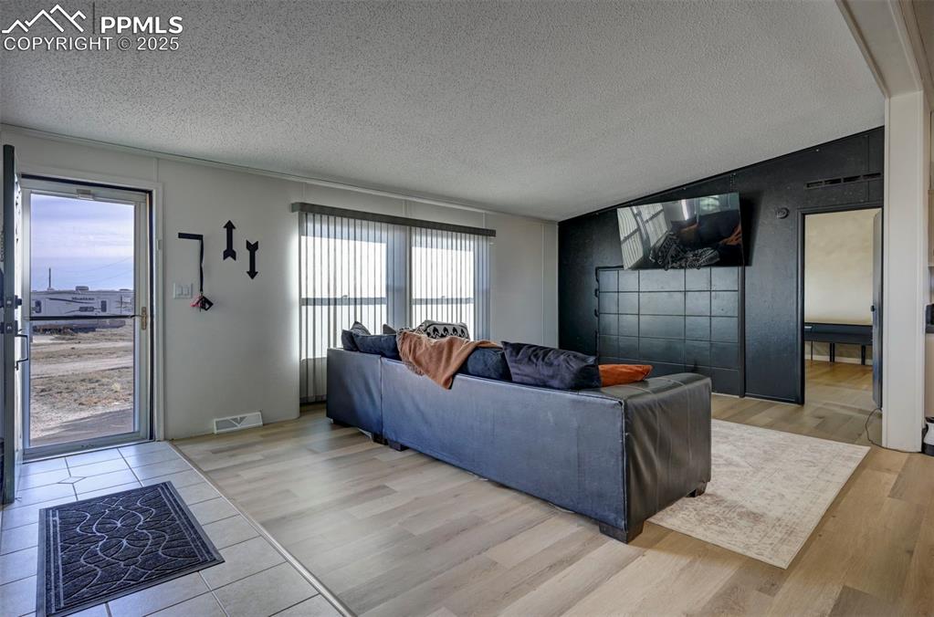 Image 6 of 40: Living room featuring vaulted ceiling, a textured ceiling, and light wood-s