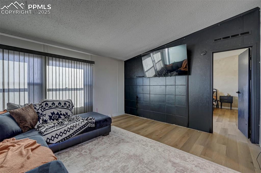 Image 8 of 40: Living area with a textured ceiling, wood finished floors, and vaulted ceil