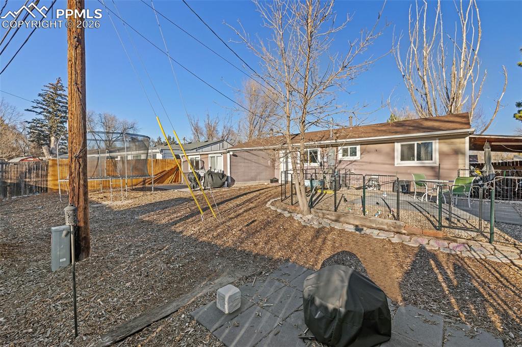 Image 16 of 19: Rear view of property featuring a fenced backyard, a playground, and a tram