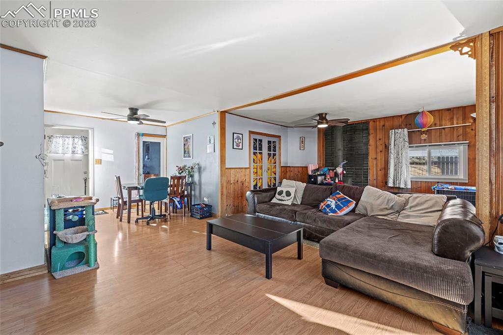 Image 5 of 19: Living room with wood walls, a ceiling fan, light wood-type flooring, and c