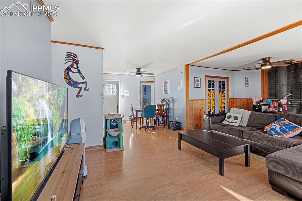 Image 6 of 19: Living room featuring a ceiling fan, wooden walls, light wood finished floo