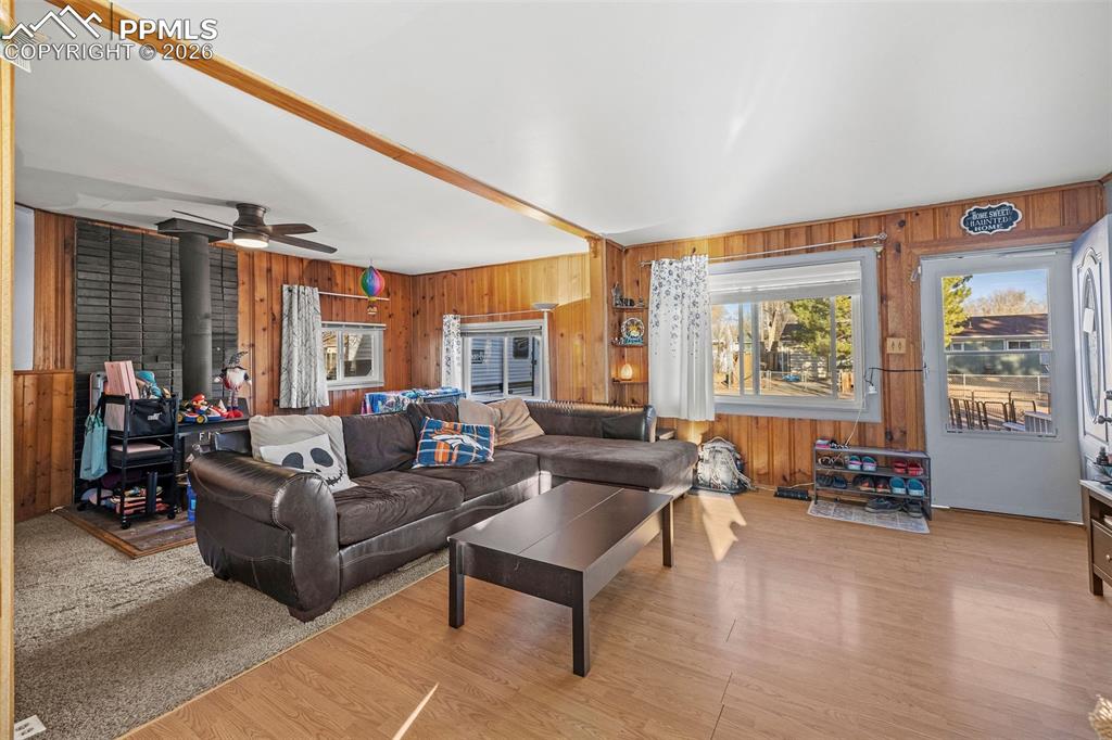 Image 7 of 19: Living room featuring wood walls, a wood stove, light wood-type flooring, a