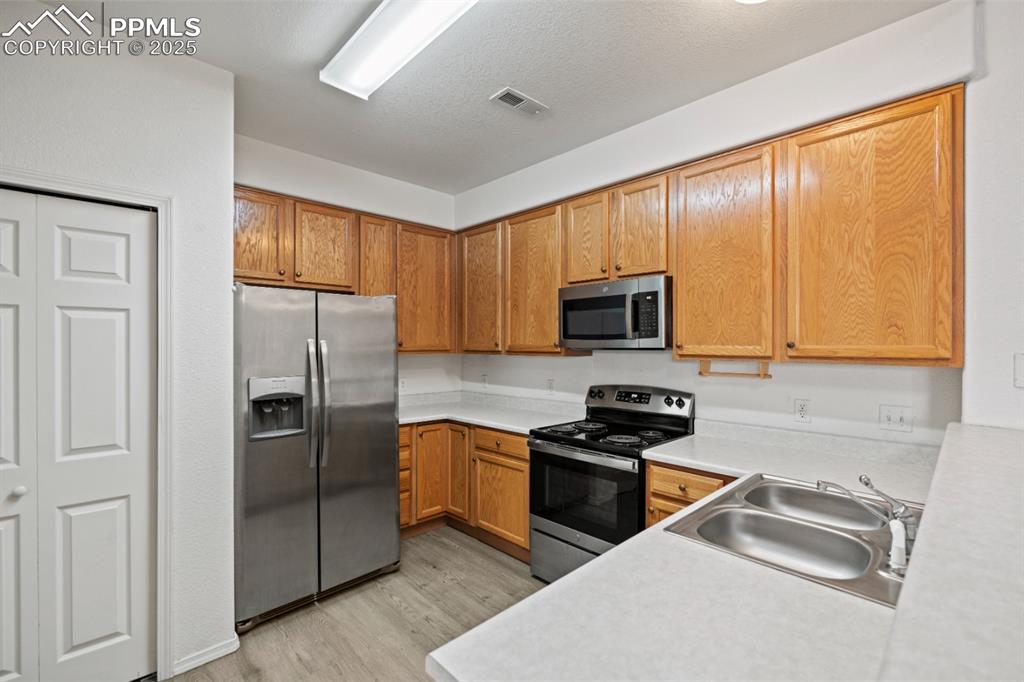 Image 11 of 22: Kitchen with stainless steel appliances, light wood-type flooring, light co