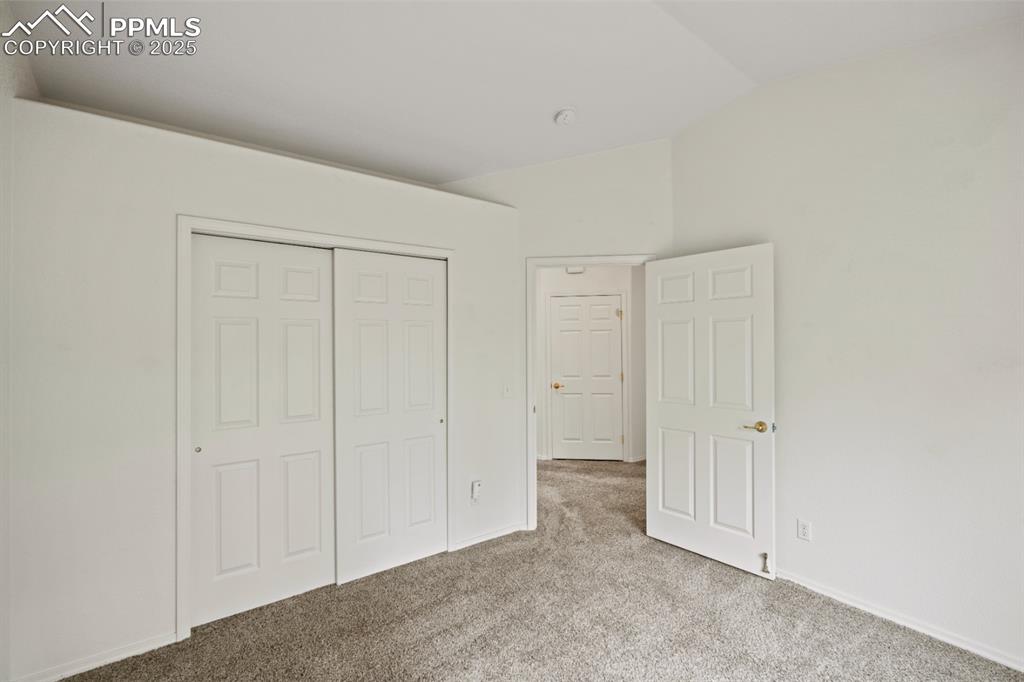 Image 12 of 22: Unfurnished bedroom with carpet flooring, vaulted ceiling, and a closet