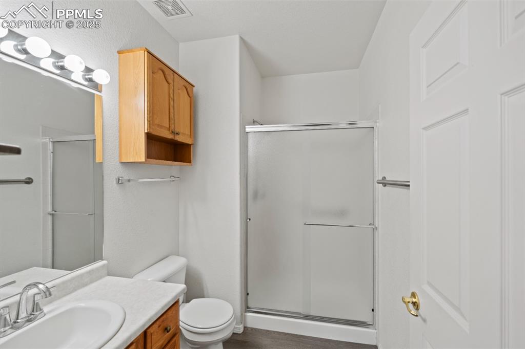 Image 18 of 22: Bathroom with a stall shower, vanity, and wood finished floors